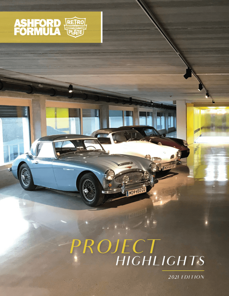 Three classic cars parked on a highly reflective, polished concrete floor in a modern showroom.