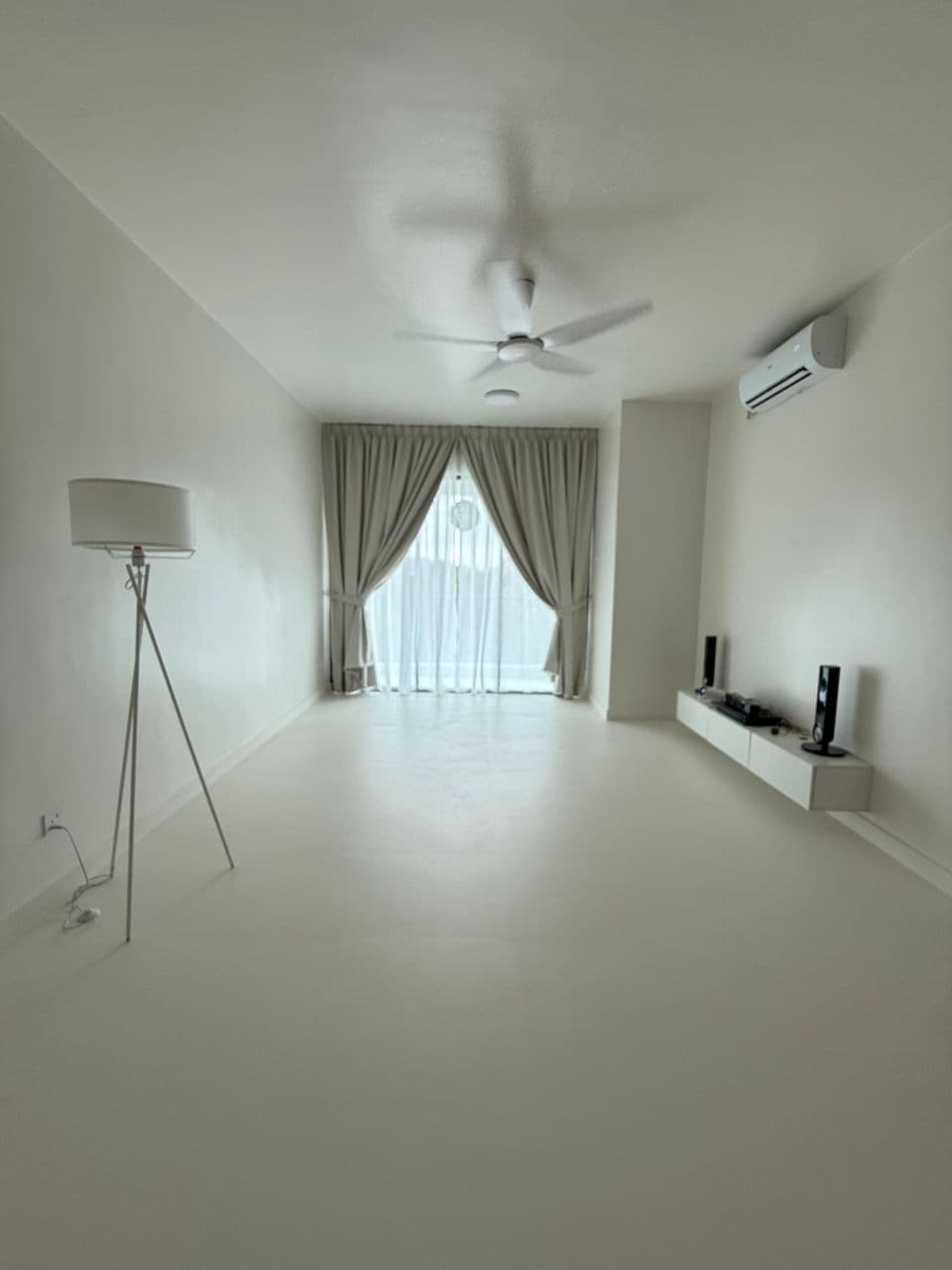 Empty minimalist white living room with tripod lamp, ceiling fan, and floating media console.