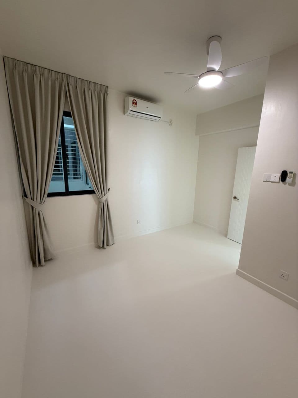 Empty white room featuring beige curtains, an air conditioner, and a lit ceiling fan.
