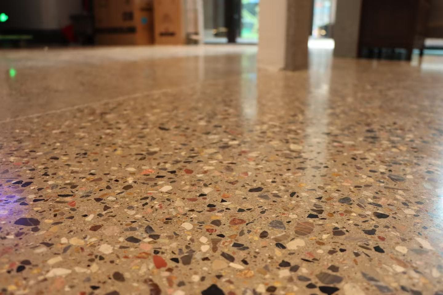 Polished terrazzo flooring with multi-colored stone chips reflecting light in a spacious indoor room.